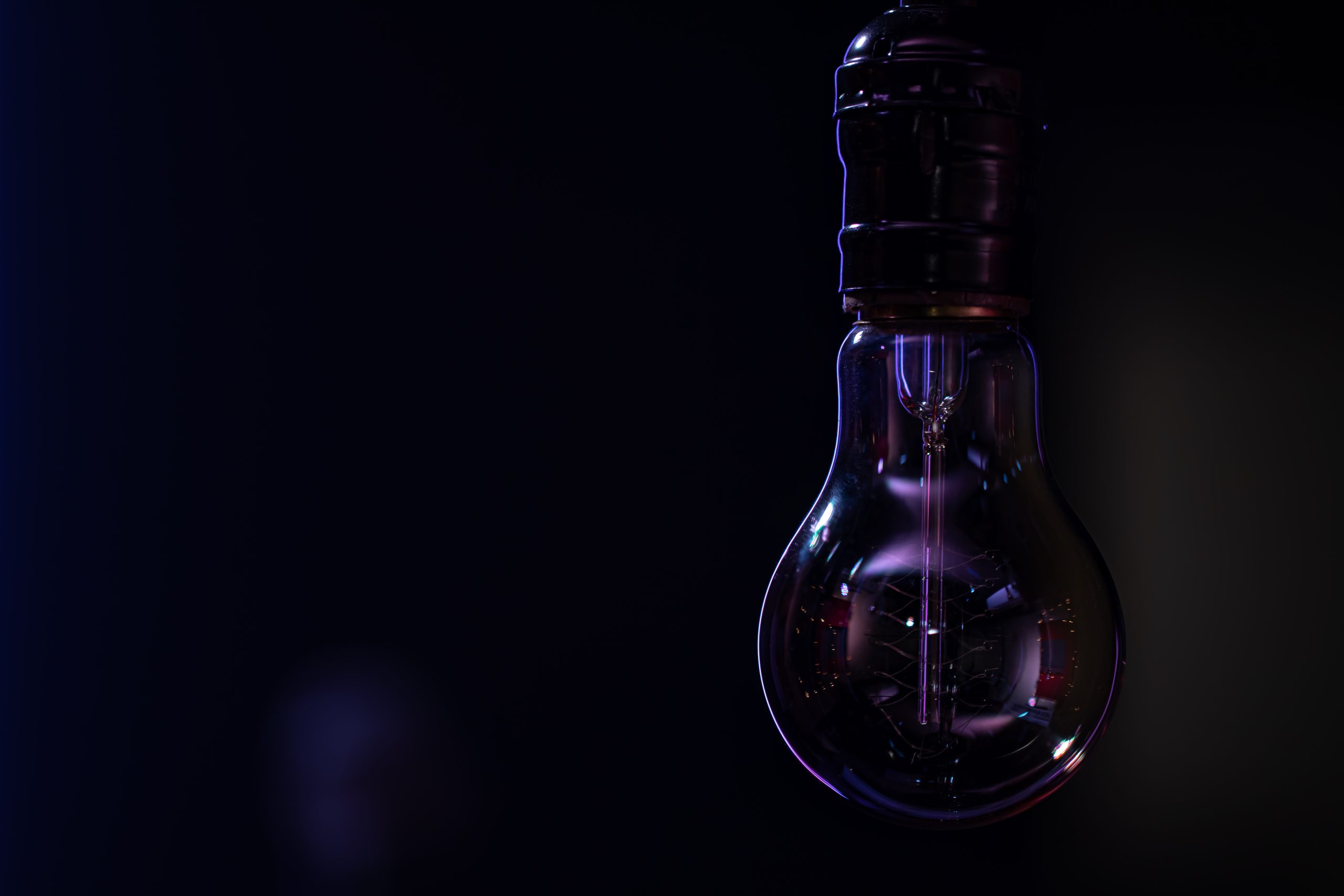 A non-luminous lamp hangs in the dark blurred background copy space.